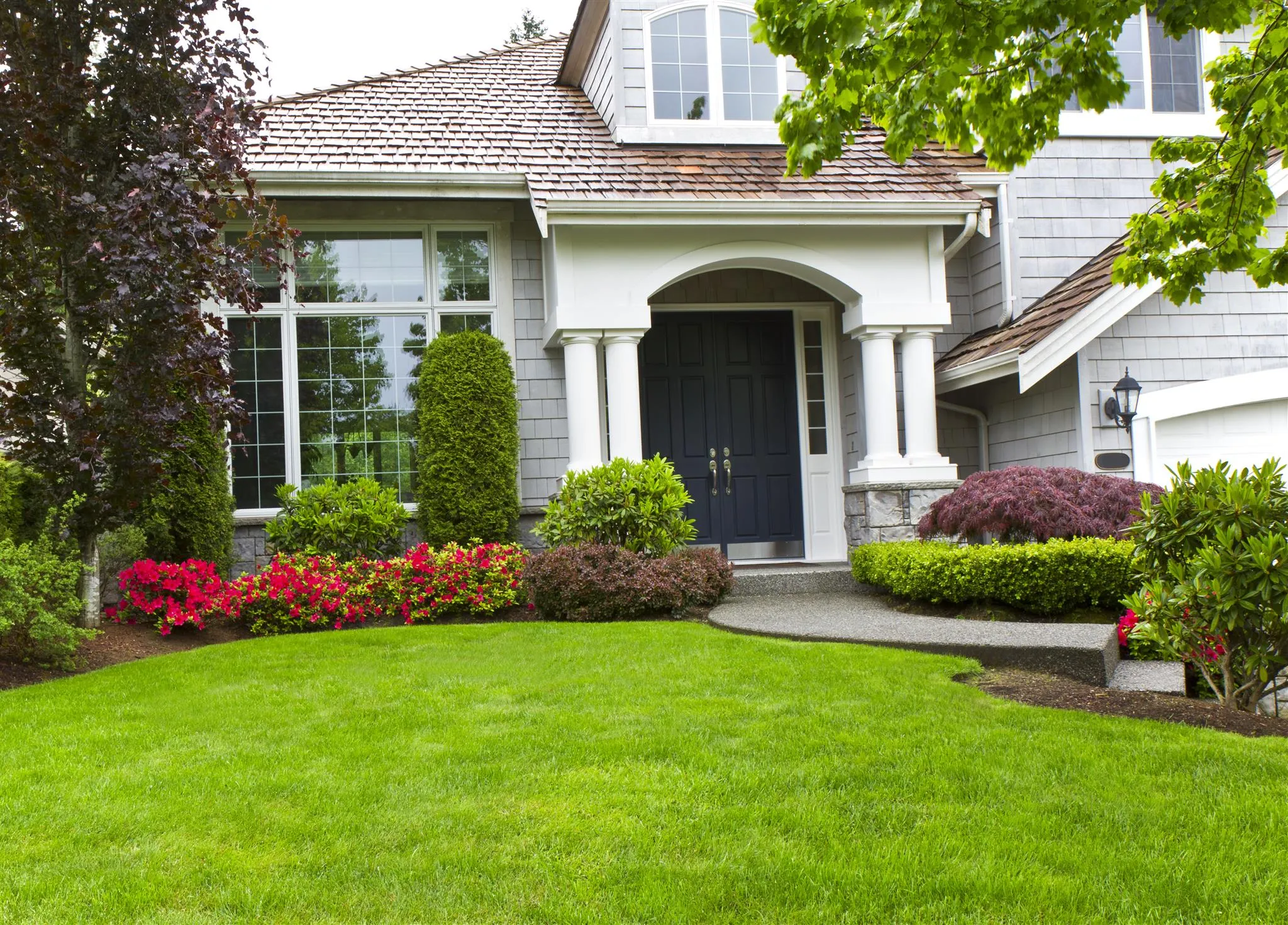 A well-maintained lawn and garden in front of a house, showcasing the lawn care services offered by Termite Lawn and Pest in Apopka, FL.