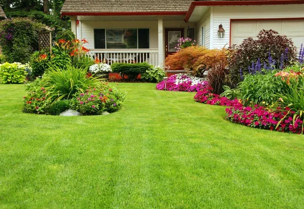 Beautifully maintained lawn and garden in front of a house, representing Termite Lawn and Pest's lawn care services in Avalon Park, FL.