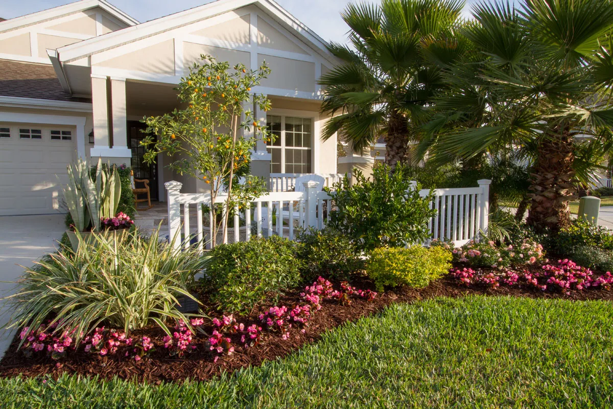 Beautifully maintained front yard with a white fence and vibrant plants in Casselberry, FL, showcasing lawn care services by Termite Lawn and Pest.