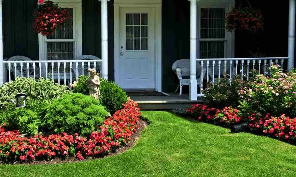 A well-maintained lawn with vibrant green grass and colorful flower beds in front of a house in Maitland, showcasing professional lawn care services.