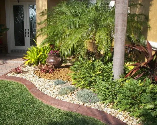 Beautifully landscaped front yard with lush green grass, vibrant plants, and palm trees, showcasing the results of expert lawn care services in Oviedo.