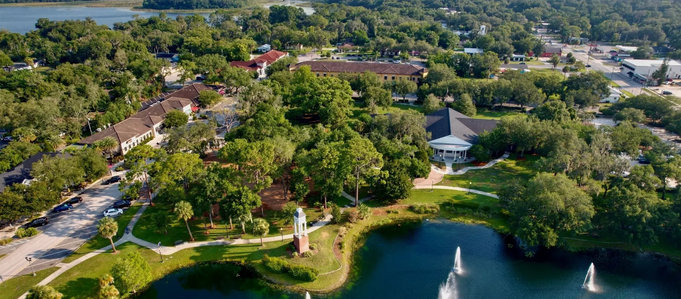 Aerial view of a scenic landscape with a lake, fountain, and surrounding greenery, showcasing the lawn care services that we provide in Lake Mary, FL.